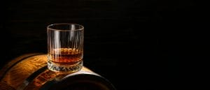 Glass of whiskey on a barrel.