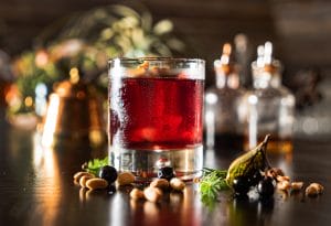 Windows Negroni cocktail with deep red hues on a table surrounded by winter greenery. Windows Distillery festive winter holiday cocktail recipes.